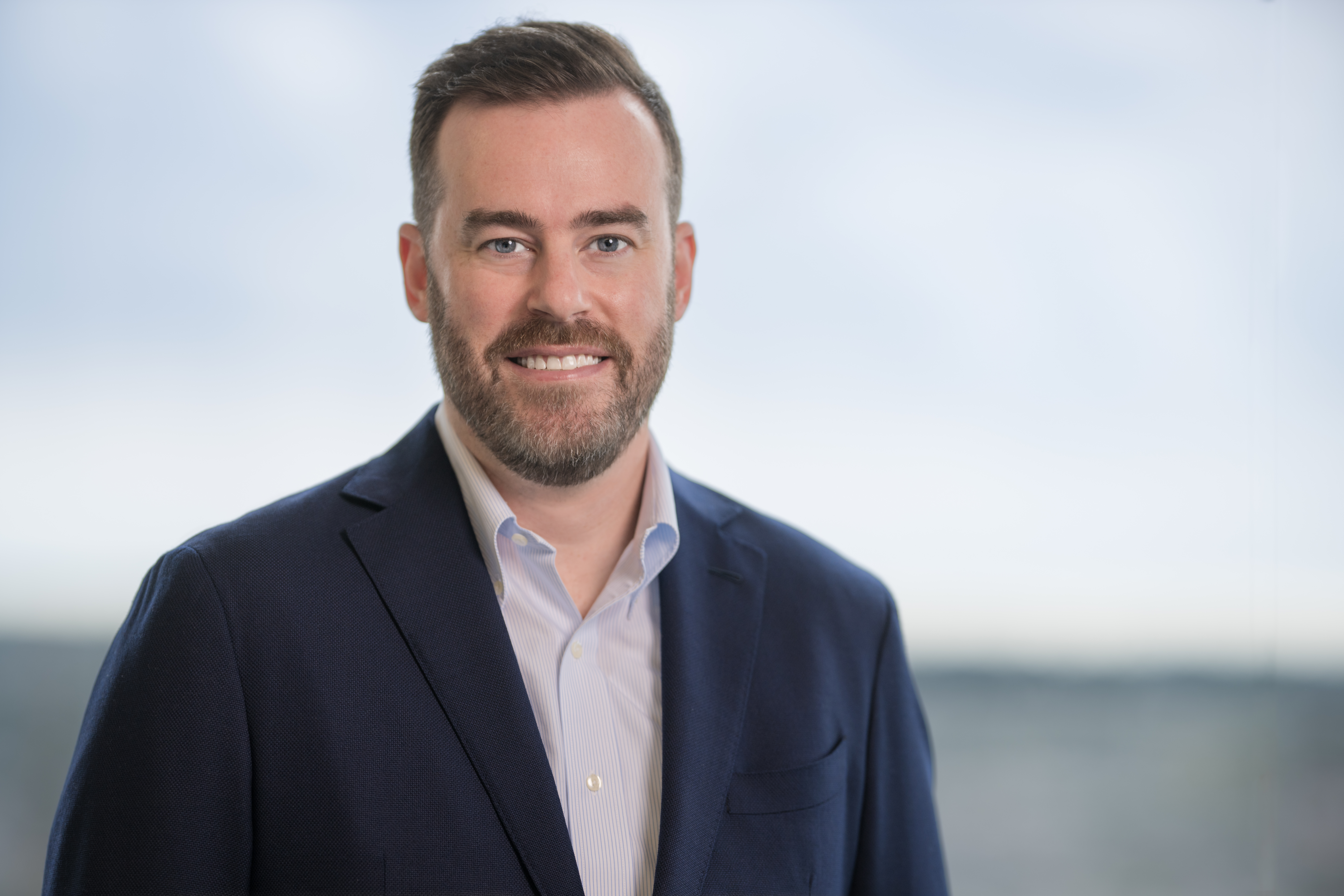 Photo of caucasian man in blue sport coat. Brown hair. Smiling.